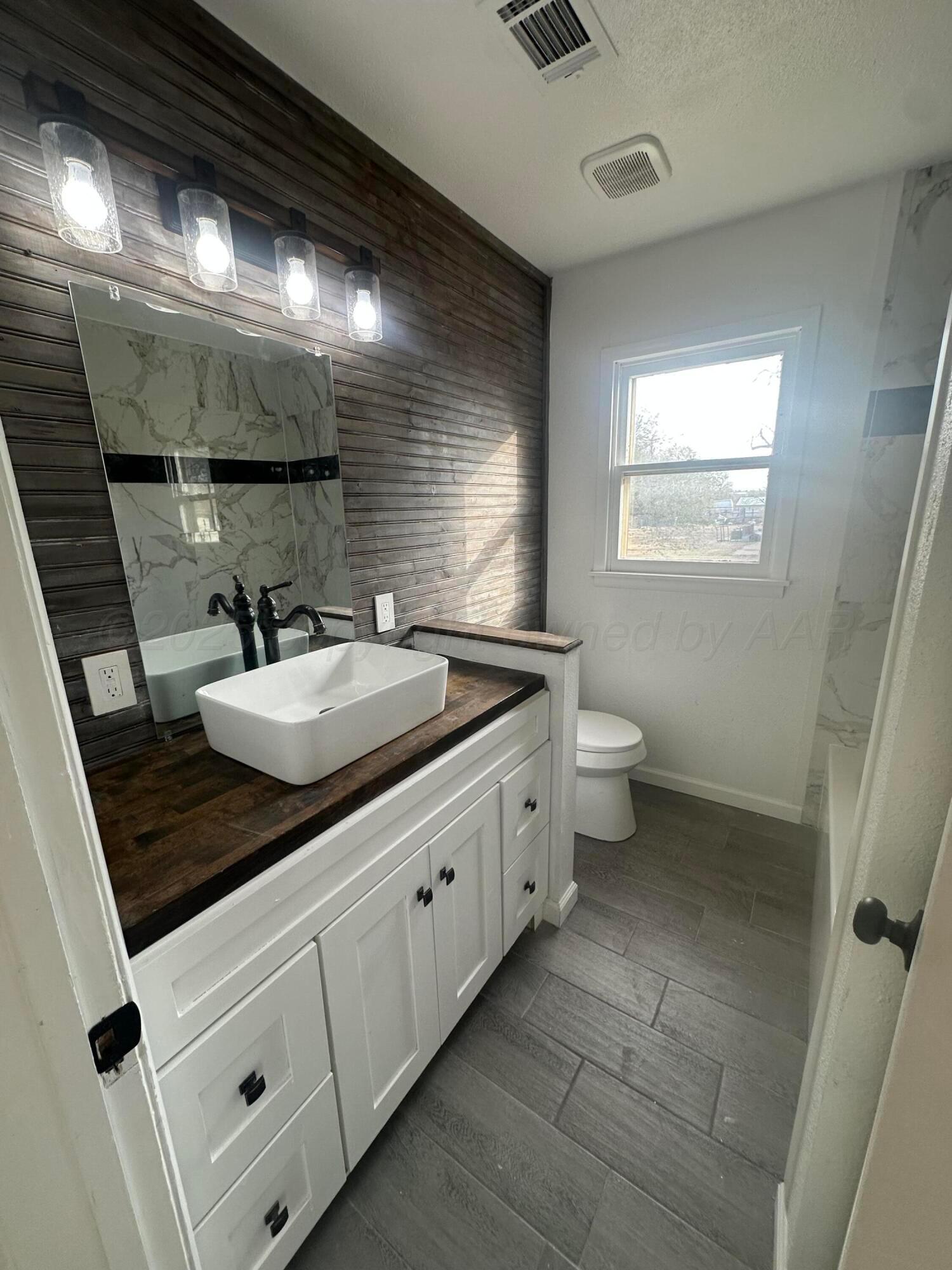 4854 Morning Drive Amarillo, TX 79108 - Photo 2 of 22 a bathroom with a double vanity sink toilet and a mirror