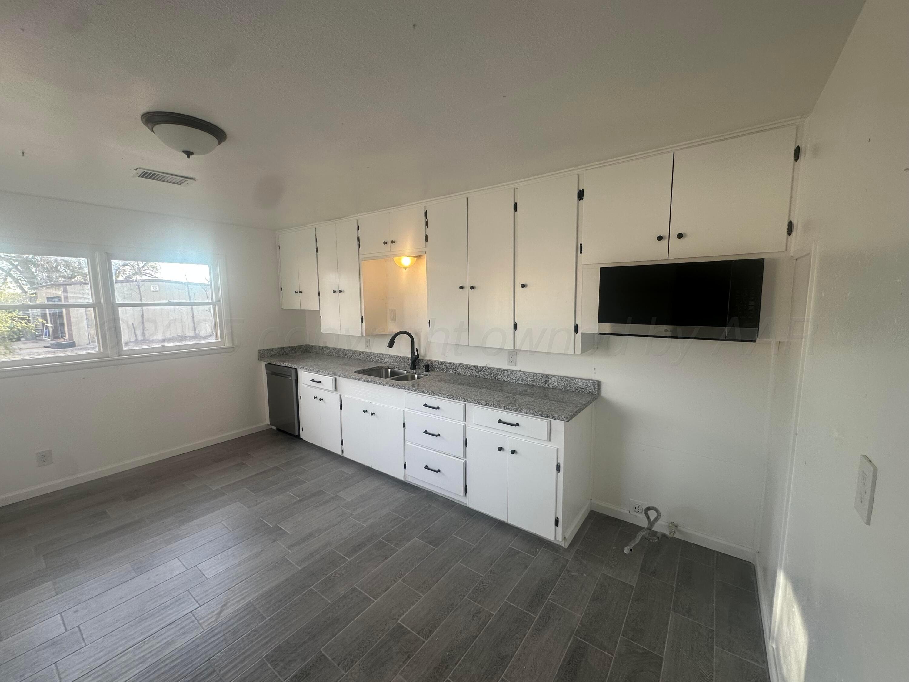 4854 Morning Drive Amarillo, TX 79108 - Photo 9 of 22 a kitchen with granite countertop white cabinets and a wooden floor