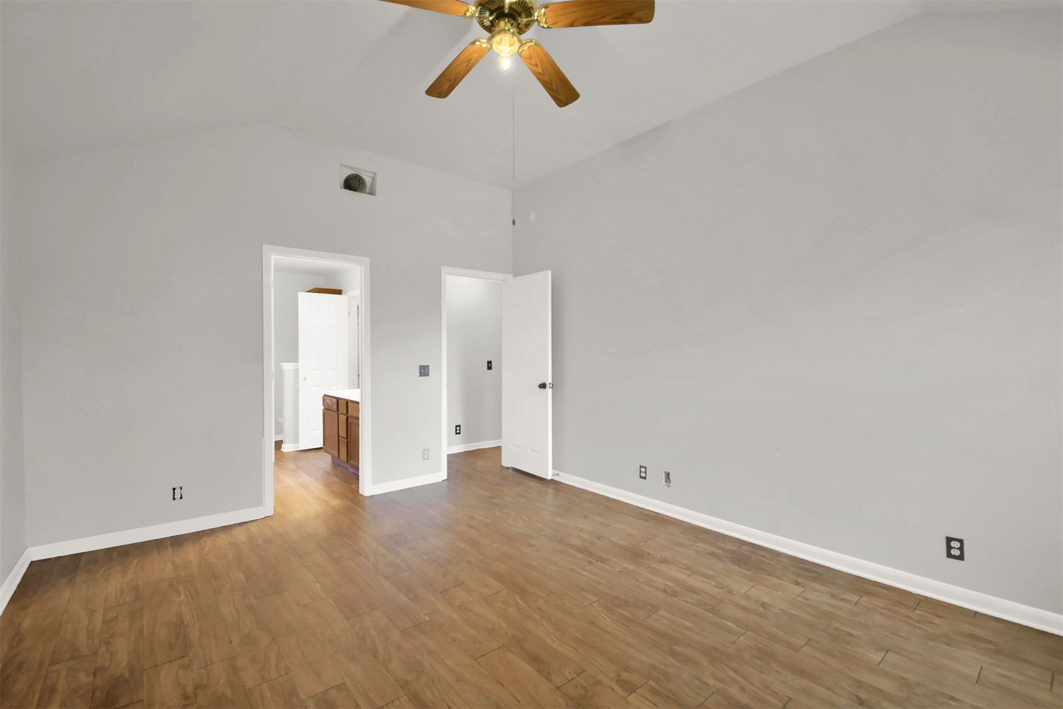 1609 Harness Raceway Street Pflugerville, TX 78660 - Photo 24 of 32 A well-lit primary bedroom features vaulted ceilings and wood flooring, offering a comfortable living space.
