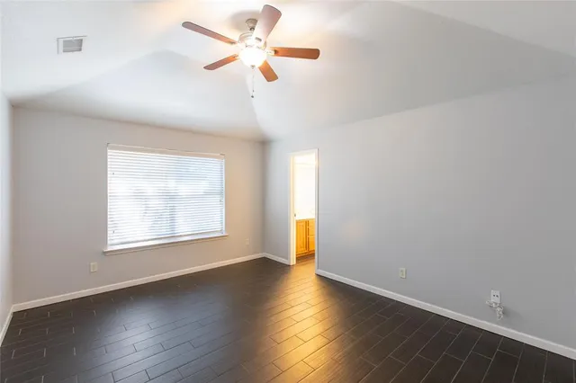 an empty room with wooden floor fan and windows