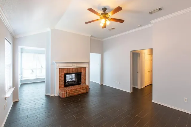 an empty room with wooden floor a fireplace and a window