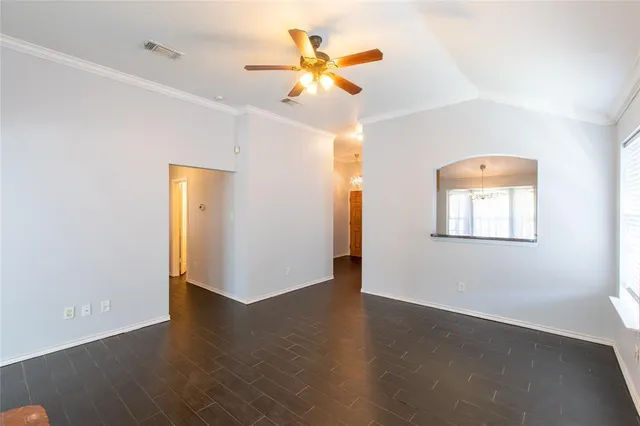 an empty room with wooden floor and a ceiling fan