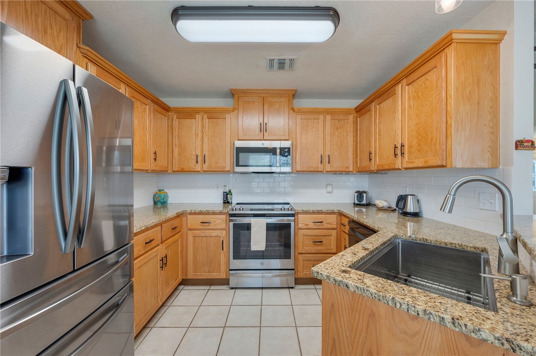 501 Riggs Street Brenham, TX 77833 - Photo 9 of 22 a kitchen with stainless steel appliances granite countertop a sink stove and refrigerator