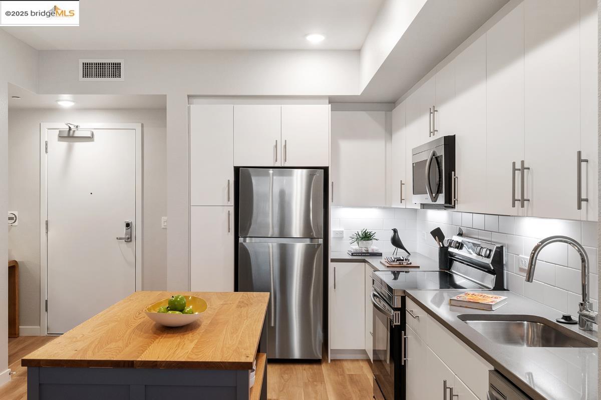 260 Brooklyn Basin Way, Unit 540 Oakland, CA 94606 - Photo 13 of 43 a kitchen with stainless steel appliances a refrigerator a sink a stove a table and chairs