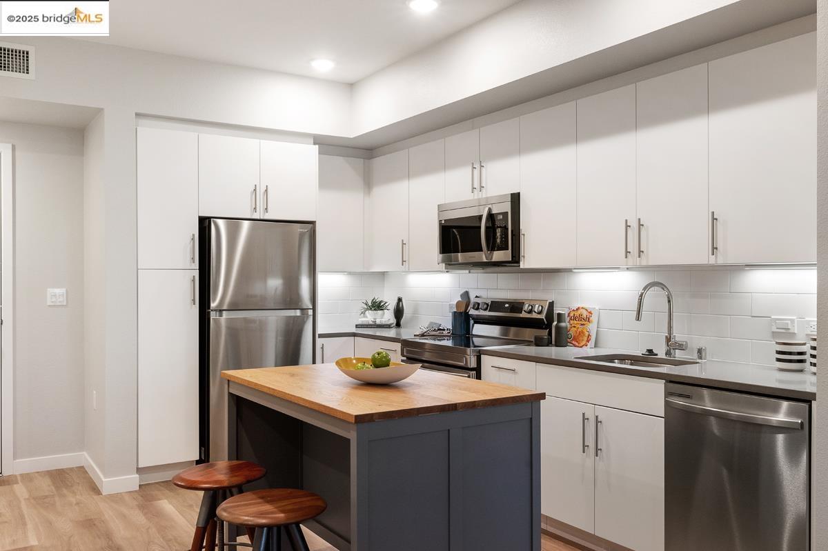 260 Brooklyn Basin Way, Unit 540 Oakland, CA 94606 - Photo 14 of 43 a kitchen with a sink a microwave a refrigerator and cabinets