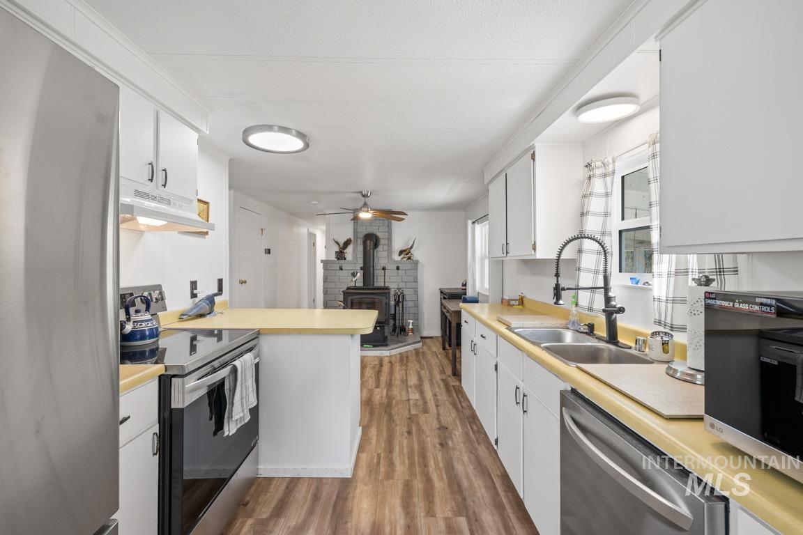 319 Pataha Street Pomeroy, WA 99347 - Photo 2 of 43 Kitchen with appliances with stainless steel finishes, light countertops, light wood finished floors, and white cabinets