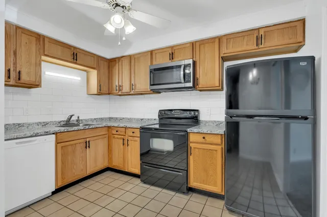 a kitchen with stainless steel appliances granite countertop a refrigerator a stove top oven a sink and dishwasher