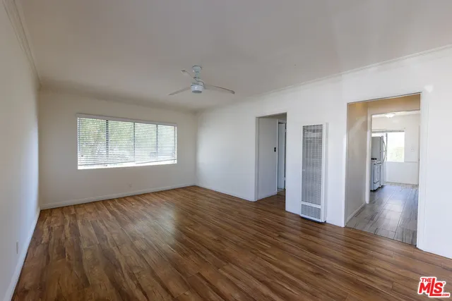 an empty room with wooden floor cabinet and windows
