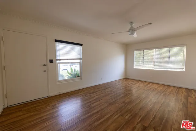 a view of an empty room with wooden floor and a window