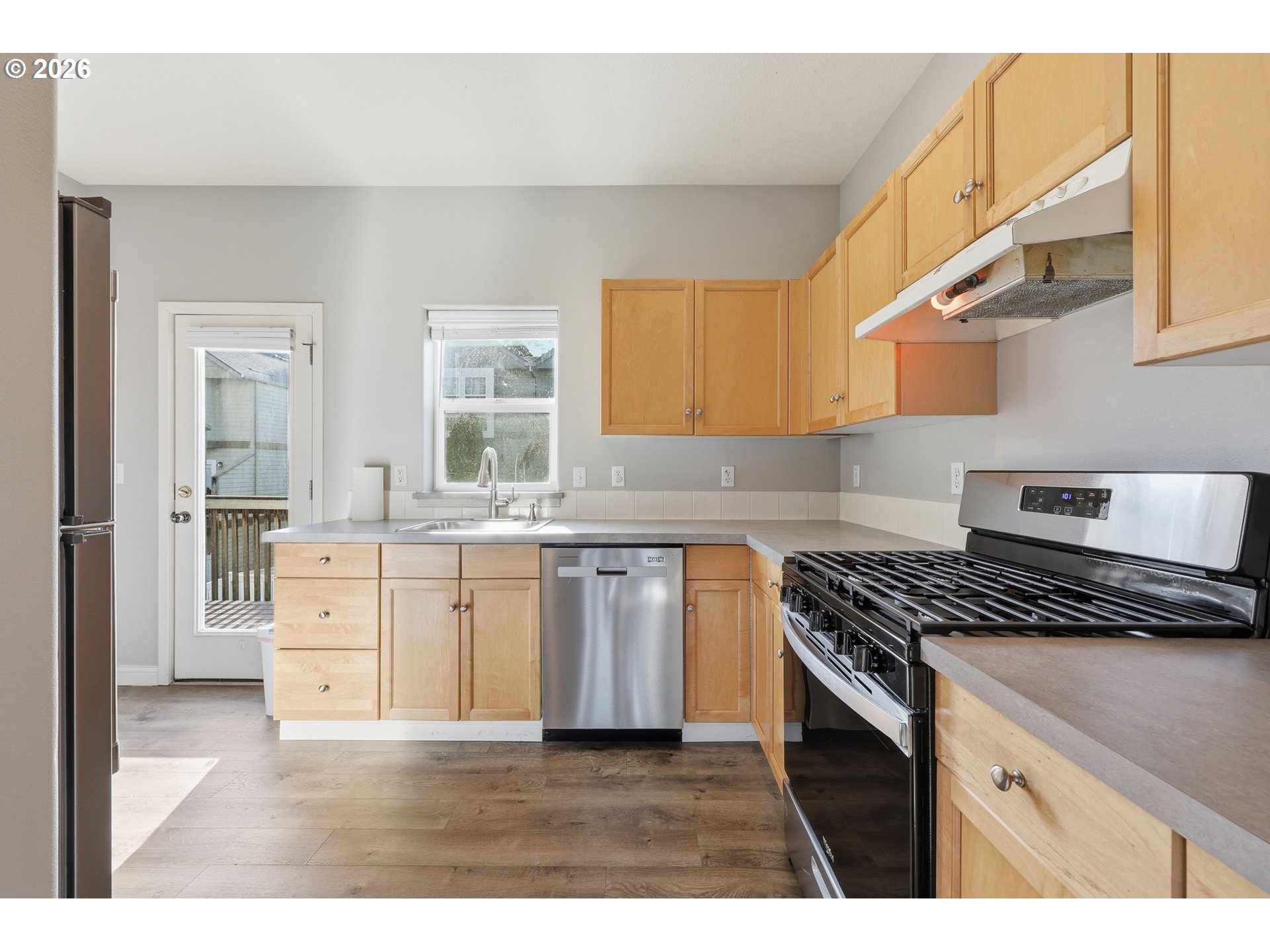 20070 Southwest Cedar Grove Lane Beaverton, OR 97003 - Photo 7 of 19 a kitchen with granite countertop a stove a sink dishwasher and a refrigerator with wooden floor