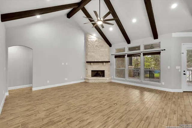 an empty room with wooden floor fan and windows