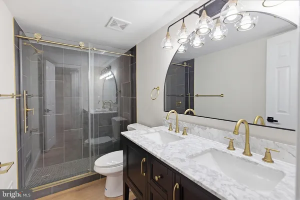 a bathroom with a granite countertop sink a toilet a mirror and shower