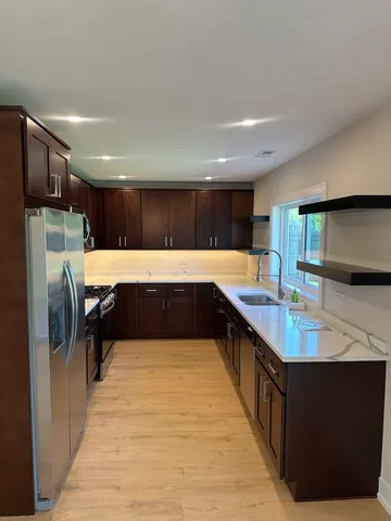 a large kitchen with kitchen island a sink dishwasher a stove and a refrigerator with wooden floor