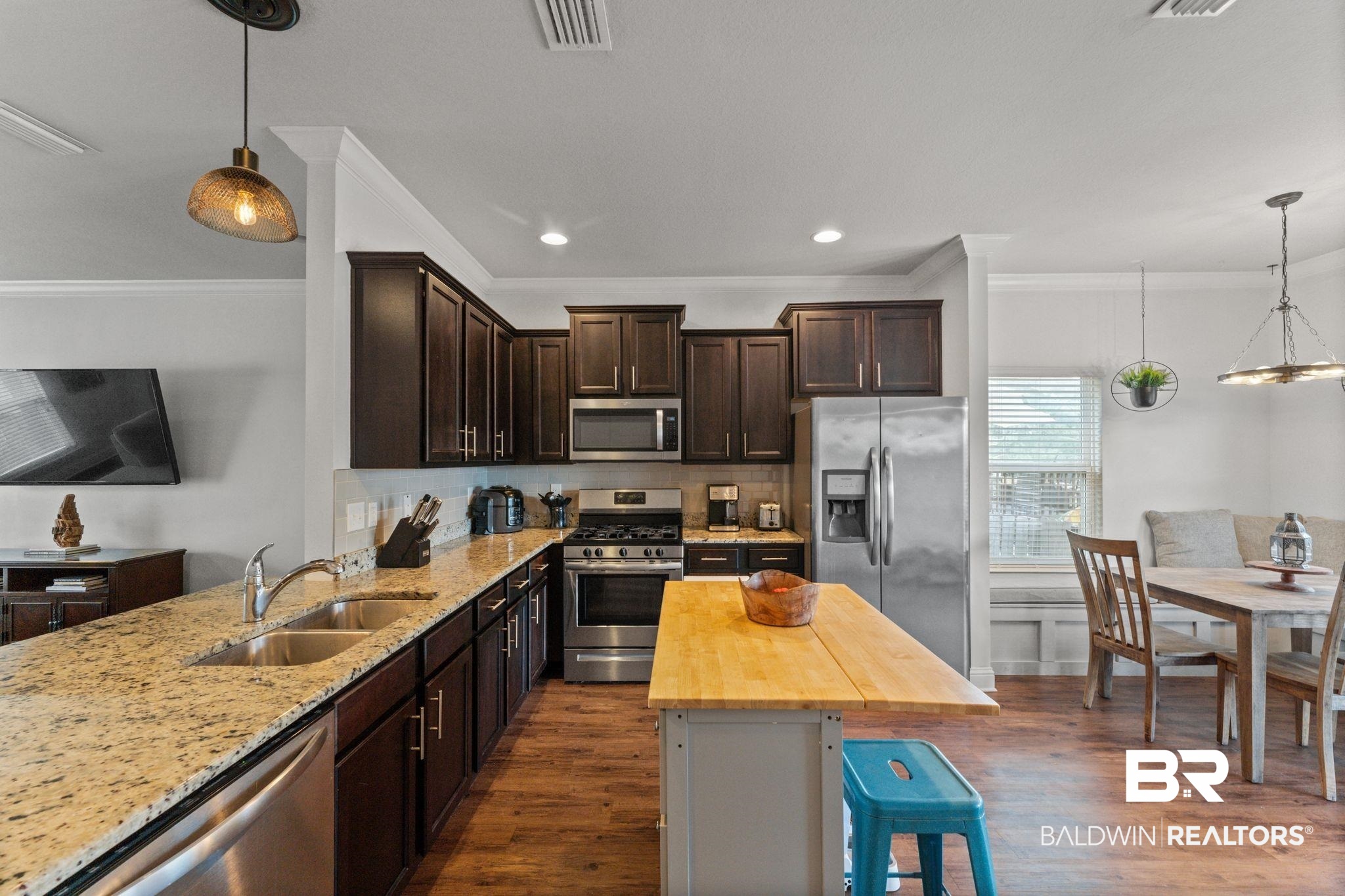 12711 Chickadee Lane Daphne, AL 36527 - Photo 10 of 39 Kitchen featuring decorative light fixtures, dark brown cabinetry, crown molding, backsplash, and appliances with stainless steel finishes