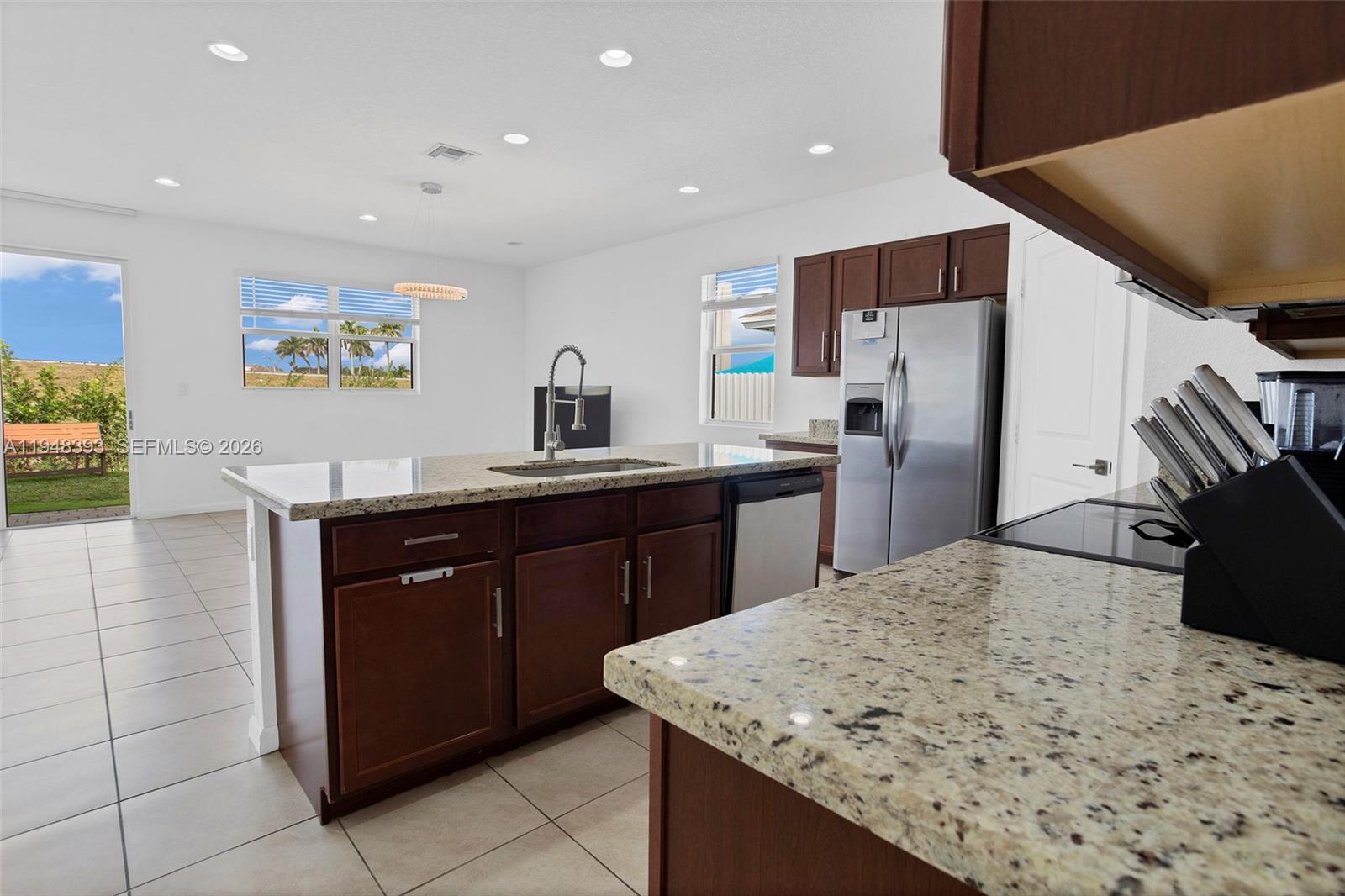 27440 Southwest 135th Ave Road Homestead, FL 33032 - Photo 29 of 75 a kitchen with stainless steel appliances kitchen island granite countertop a refrigerator a sink a stove with wooden cabinets