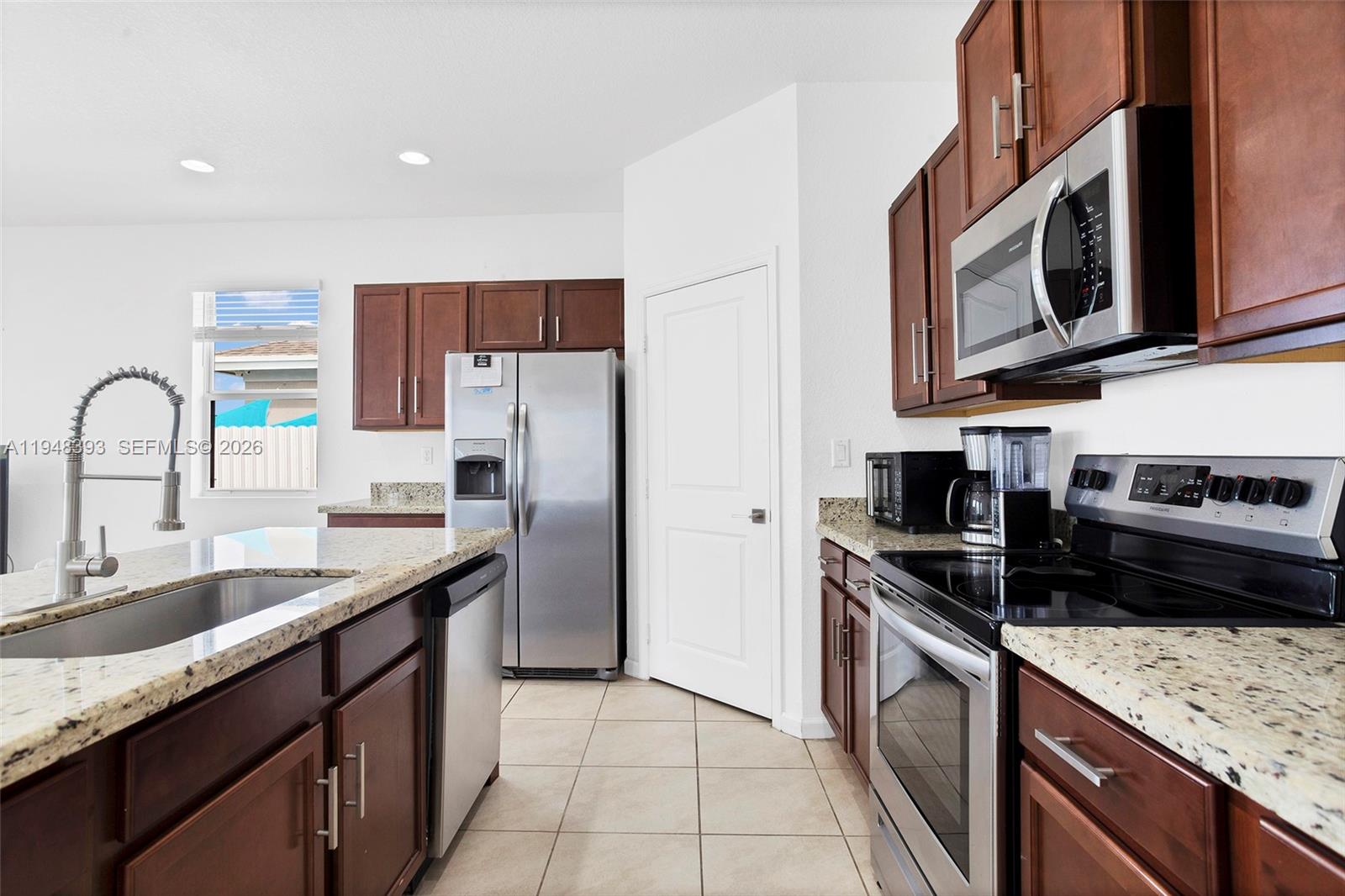 27440 Southwest 135th Ave Road Homestead, FL 33032 - Photo 31 of 75 a kitchen with stainless steel appliances granite countertop a sink stove and refrigerator