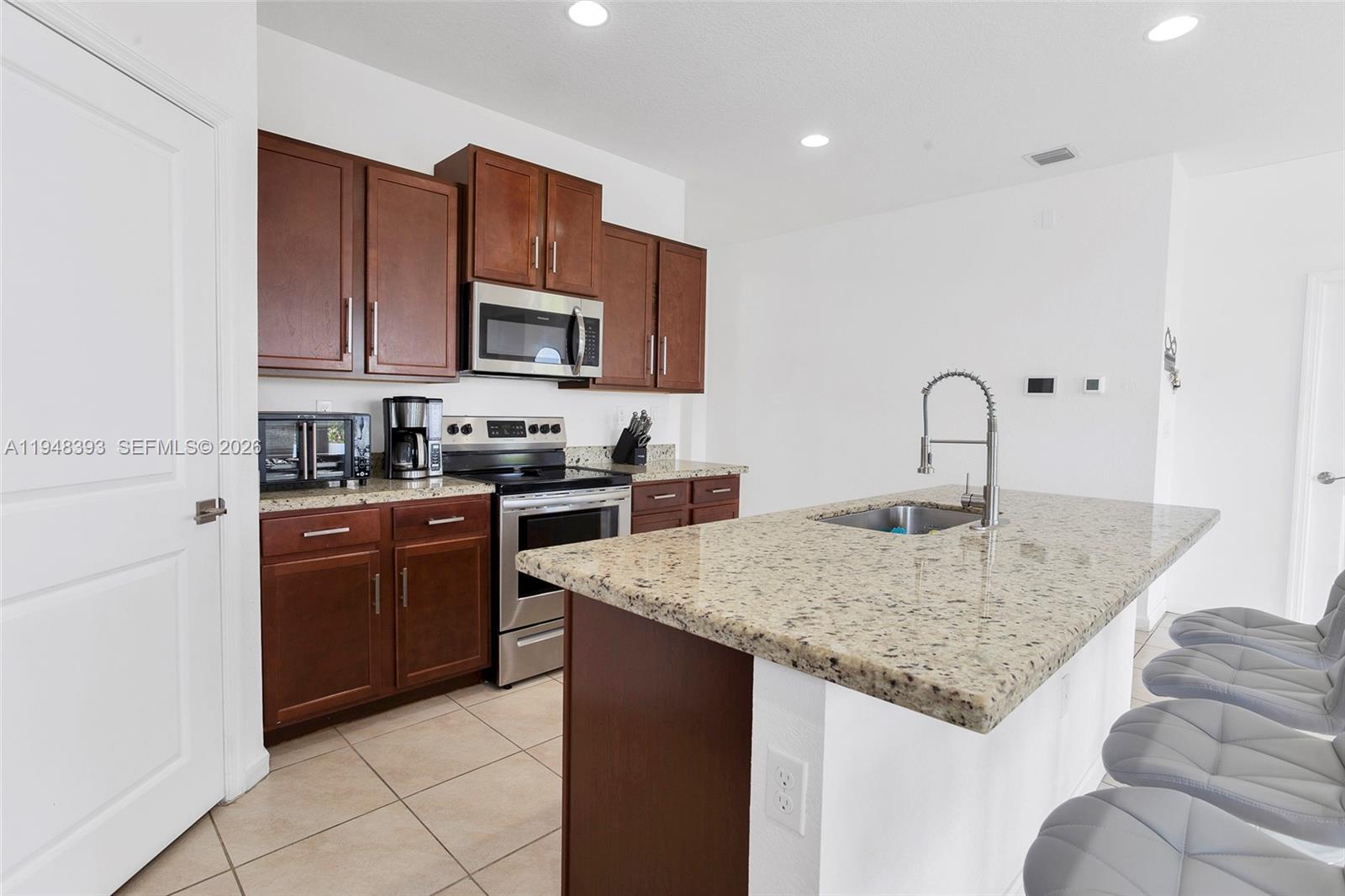 27440 Southwest 135th Ave Road Homestead, FL 33032 - Photo 38 of 75 a kitchen with stainless steel appliances granite countertop a sink dishwasher and stove with wooden cabinets