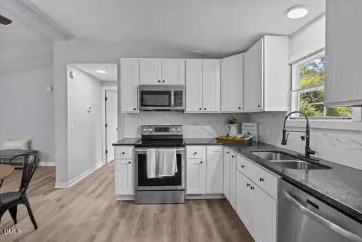 a kitchen with granite countertop white cabinets white stainless steel appliances and a sink