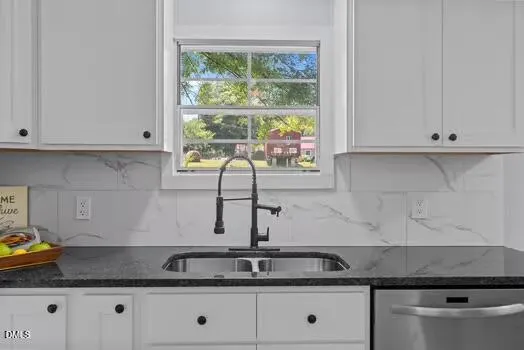 a kitchen that has a lot of white cabinets and wooden floor