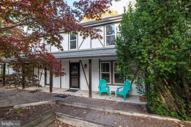 a view of house with outdoor seating and covered with trees