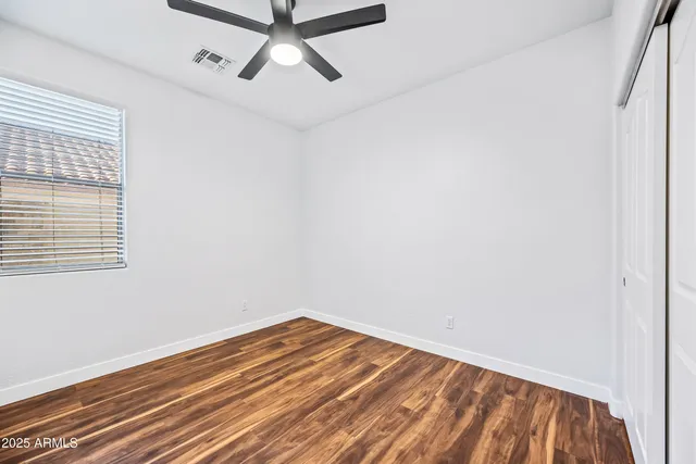 a view of a room with wooden floor and a ceiling fan