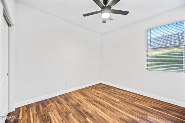 an empty room with a window and ceiling fan