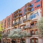 a front view of a building with lot of cars and trees