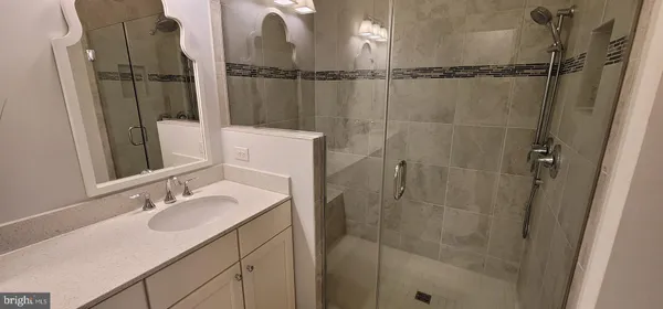 a bathroom with a sink vanity granite and shower