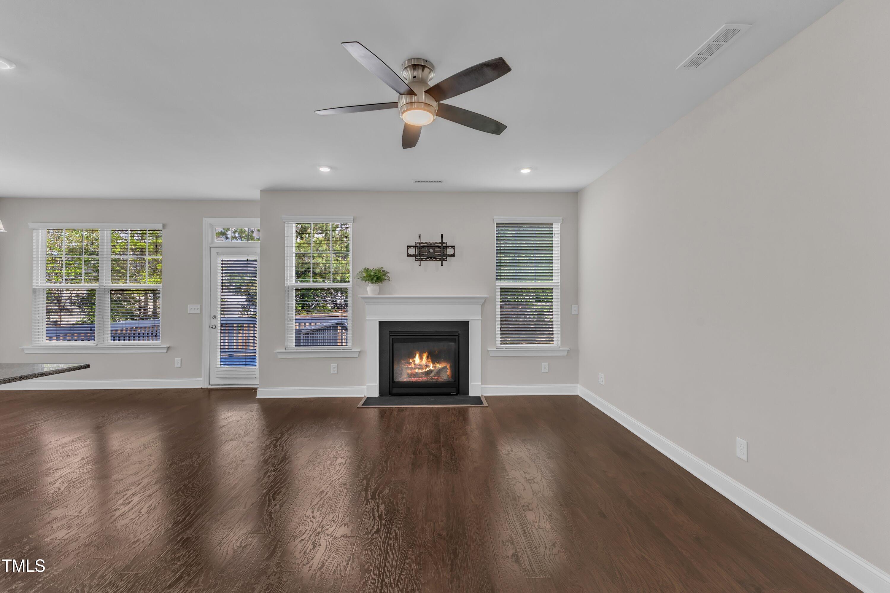 4252 Rockdell Hall Street Raleigh, NC 27616 - Photo 19 of 64 an empty room with wooden floor fireplace and windows