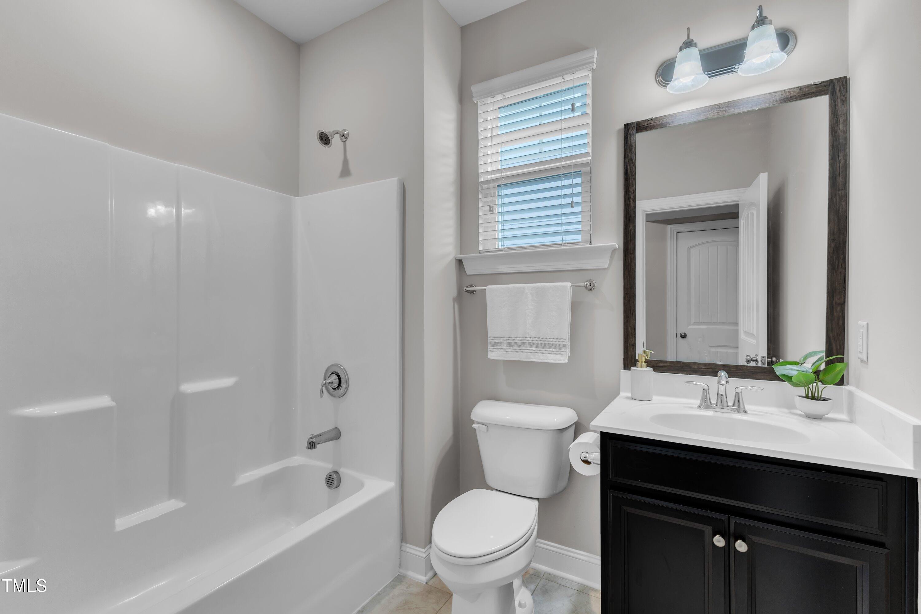 4252 Rockdell Hall Street Raleigh, NC 27616 - Photo 29 of 64 a bathroom with a sink a toilet a mirror a vanity and bathtub