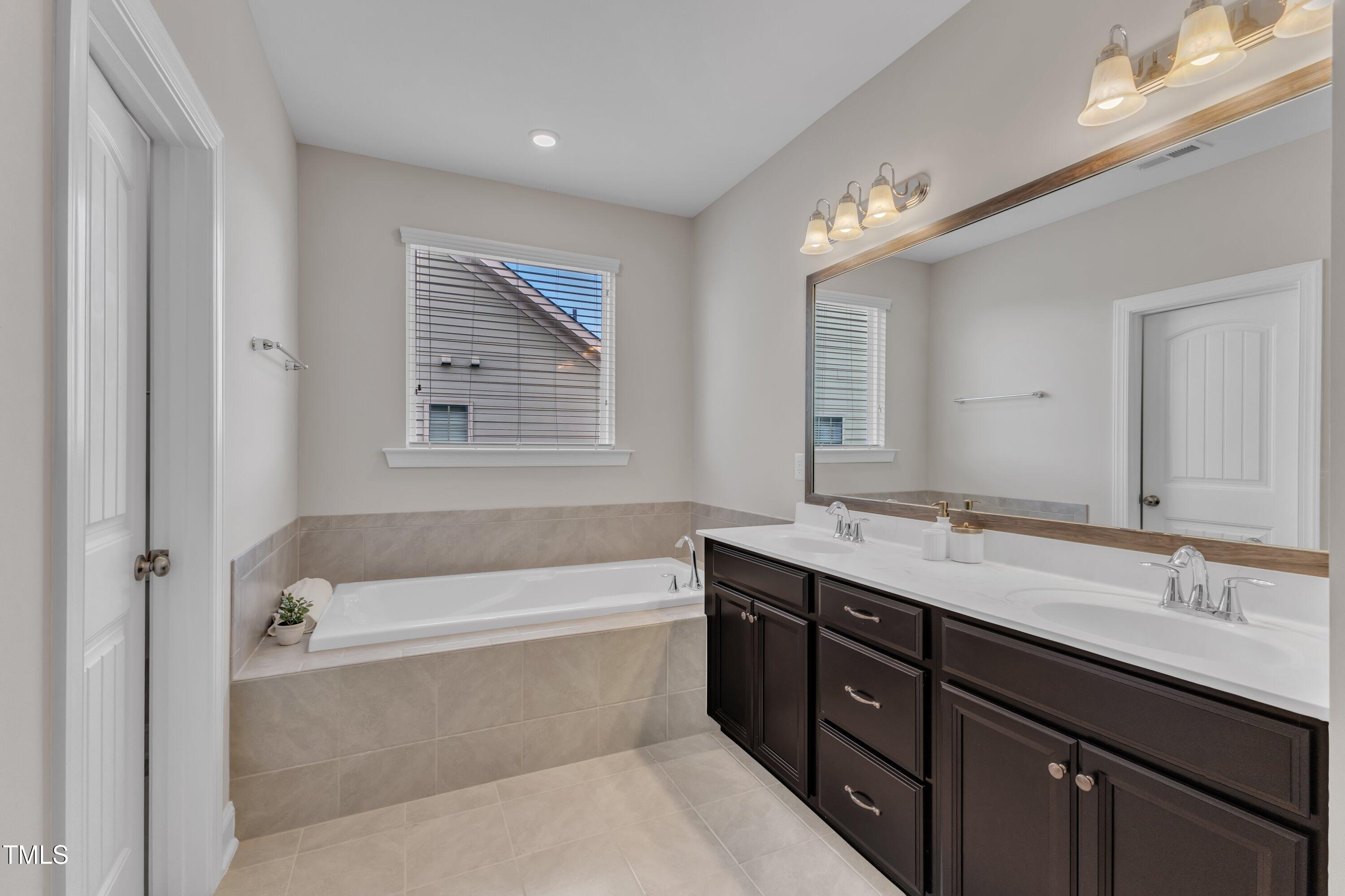 4252 Rockdell Hall Street Raleigh, NC 27616 - Photo 6 of 64 a bathroom with a tub a double vanity sink and a mirror