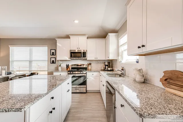 a kitchen with stainless steel appliances granite countertop a sink stove refrigerator and cabinets