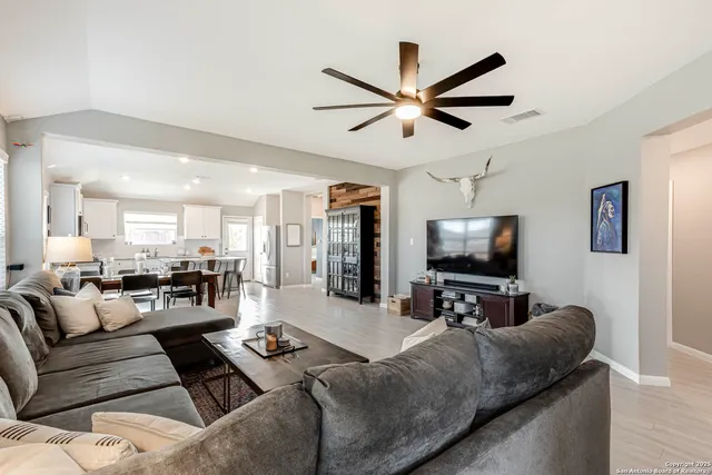 a living room with furniture and a flat screen tv with kitchen view