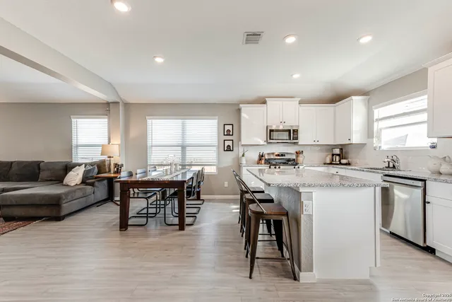 a kitchen with stainless steel appliances granite countertop a table chairs sink refrigerator and cabinets