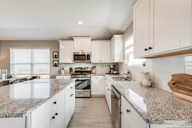 a kitchen with stainless steel appliances granite countertop a sink stove refrigerator and cabinets