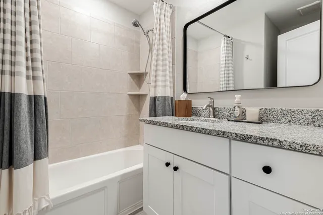 a bathroom with a granite countertop sink mirror and a bathtub