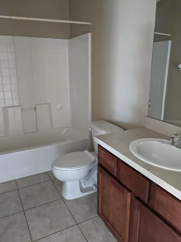 a bathroom with a granite countertop bathtub sink vanity and toilet