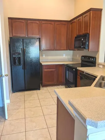 a kitchen with stainless steel appliances granite countertop a refrigerator a stove and a sink with wooden cabinets