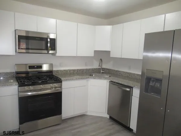a kitchen with granite countertop white cabinets stainless steel appliances and a sink