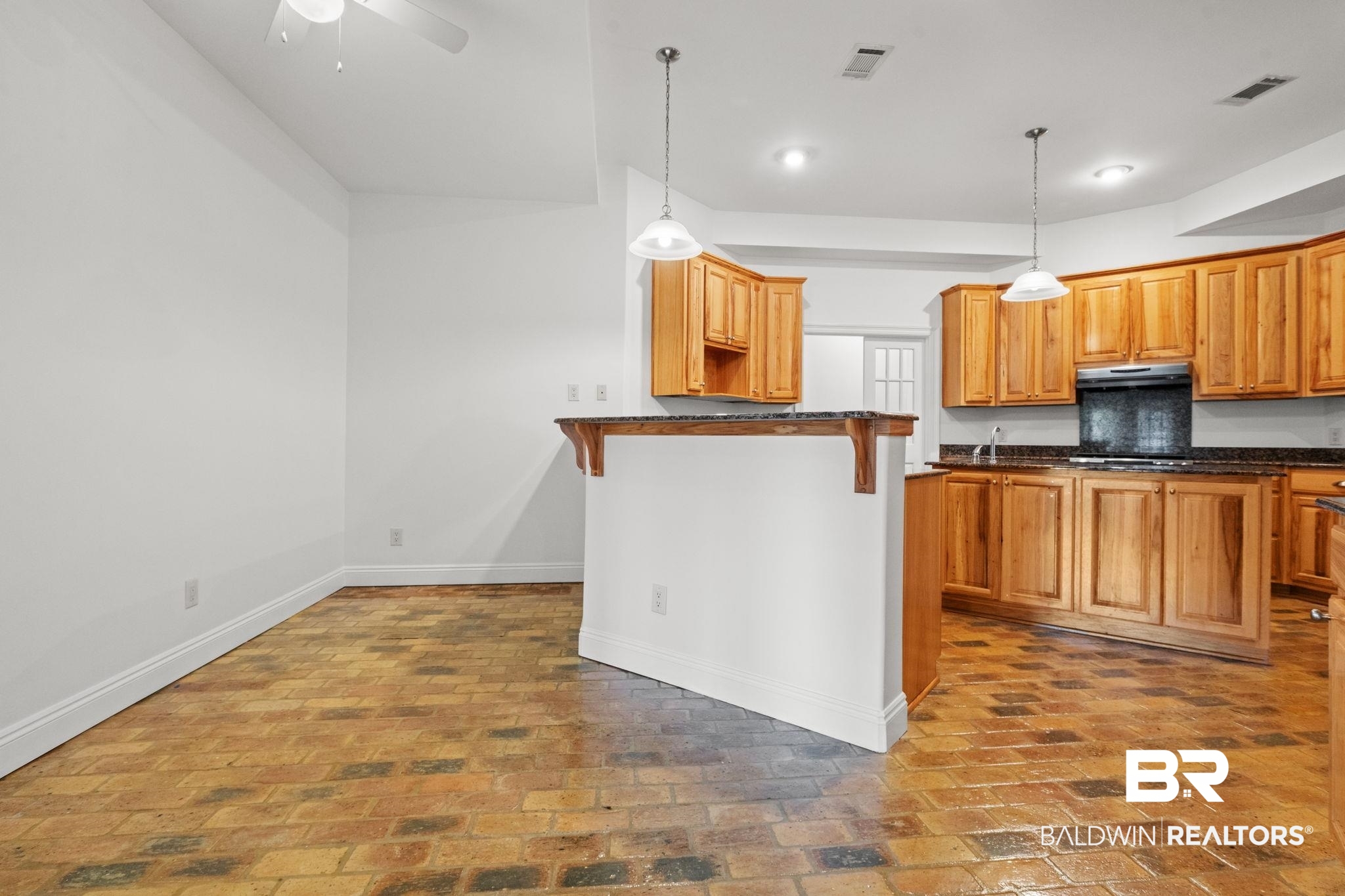 29634 St George Street Daphne, AL 36526 - Photo 16 of 47 Kitchen featuring brick flooring, decorative light fixtures, a kitchen breakfast bar, and wood finish cabinetry
