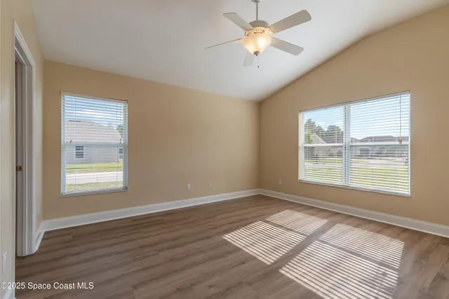 a view of an empty room with a window and wooden floor