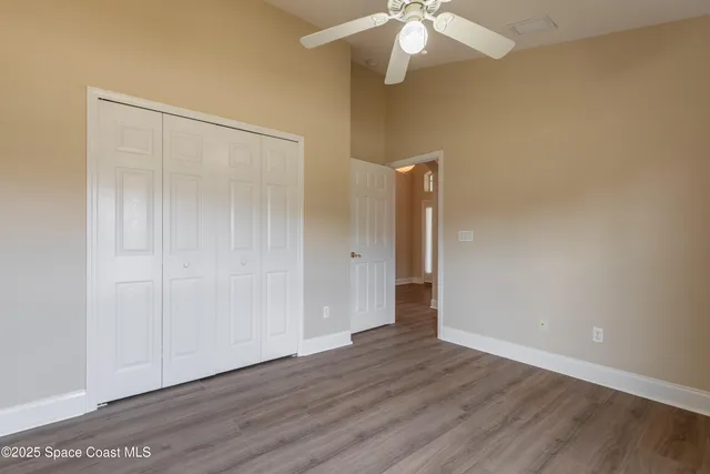 an empty room with wooden floor and a ceiling fan