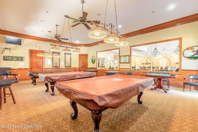 a room with lots of tables a chandelier and a projector screen