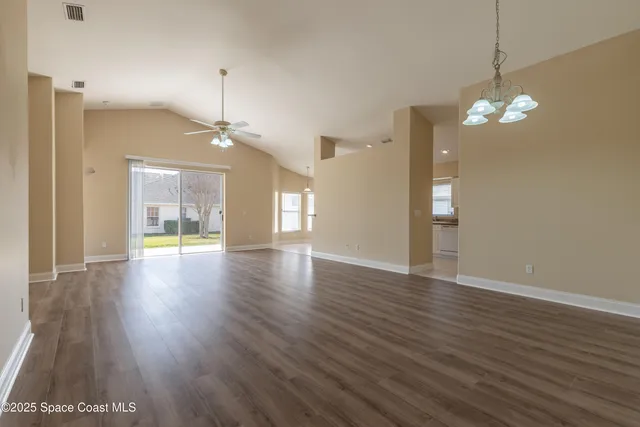 a view of a room with wooden floor chandelier and windows