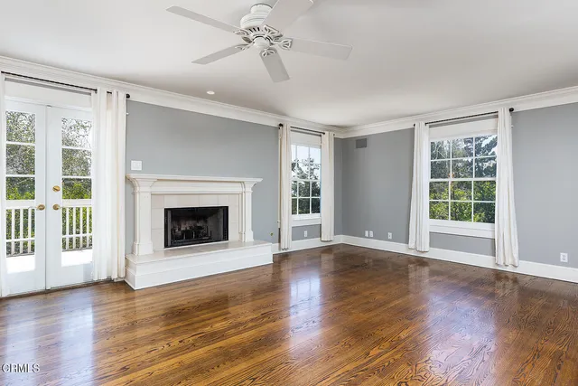 a view of an empty room with wooden floor fireplace and a window