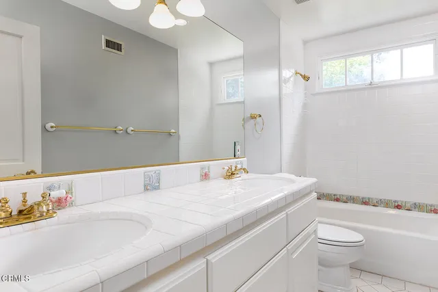 a bathroom with a granite countertop sink a toilet and a mirror