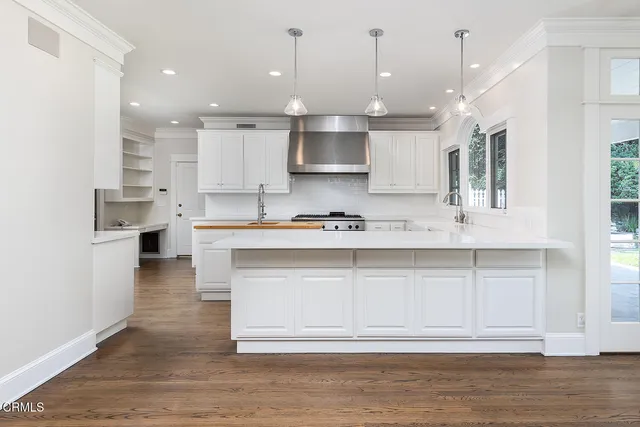 a large white kitchen with lots of counter space wooden cabinets and stainless steel appliances