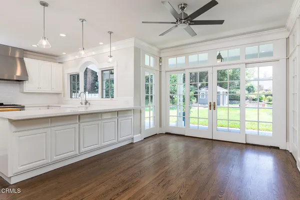 a open kitchen with granite countertop a stove top oven a sink and wooden floors