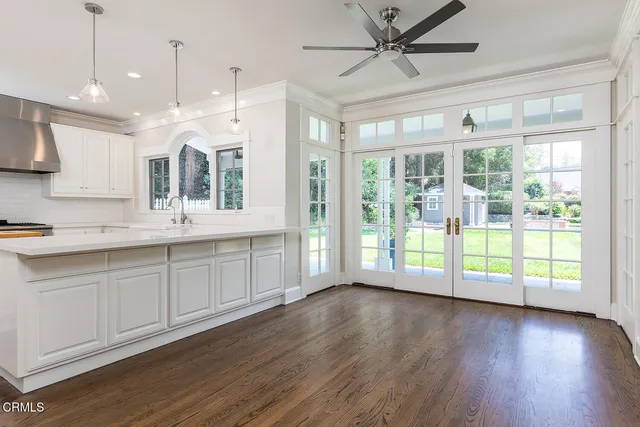 a open kitchen with granite countertop a stove top oven a sink and wooden floors