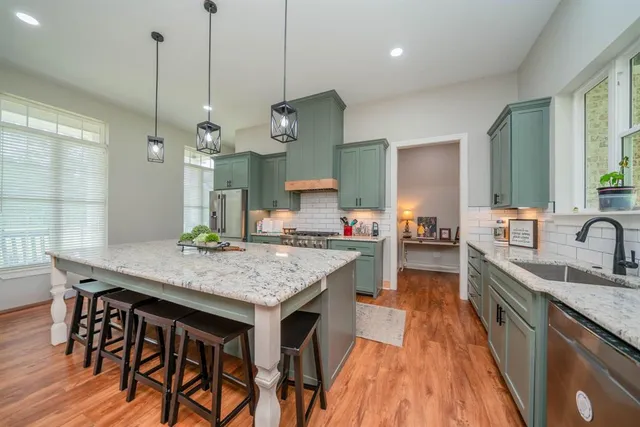 a kitchen with a stove a sink a refrigerator and chairs